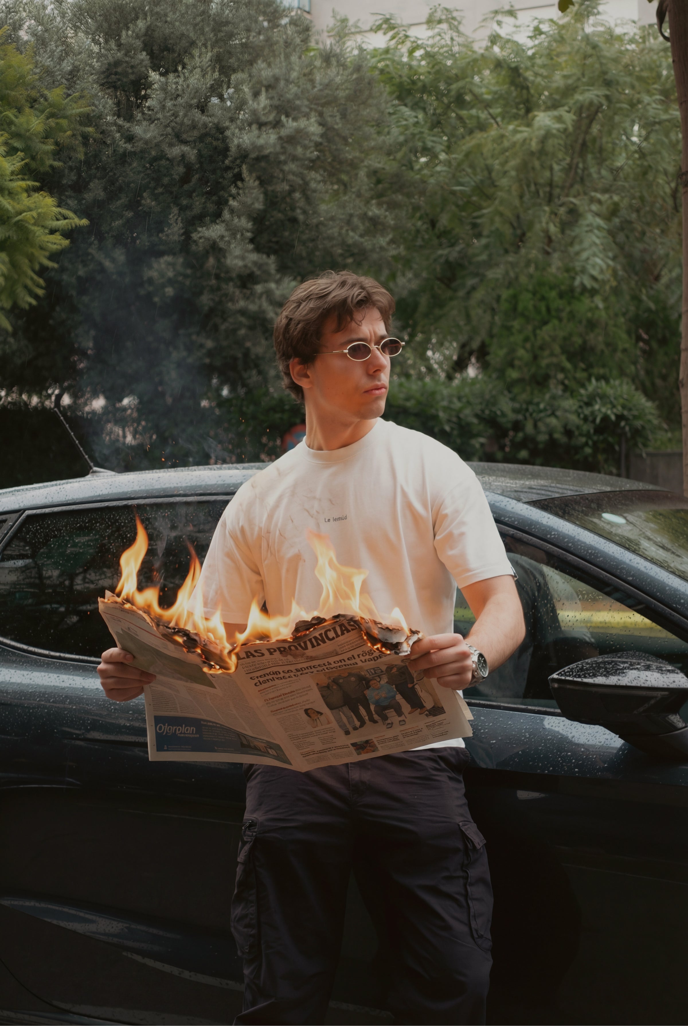 Model wearing white oversized Le Lemud t-shirt holding burning newspaper, Collection 001 lookbook