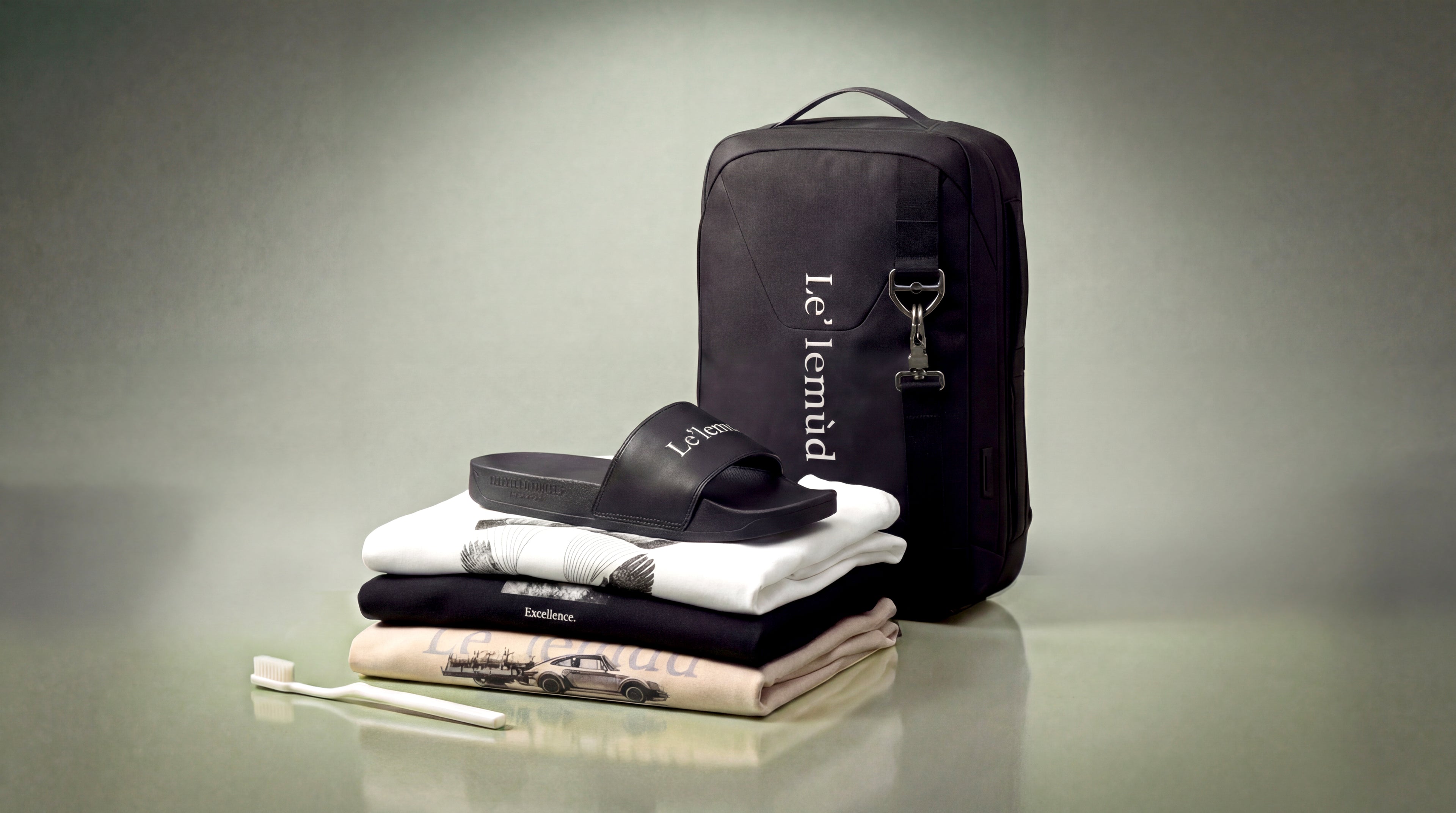 Lelemud Collection 001 wireless parachute featuring black backpack, slides, graphic t-shirts, and travel essentials in premium lifestyle product photography