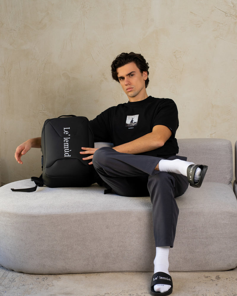 Model wearing Lelemud Excellence black tee with and branded slides in lifestyle photography