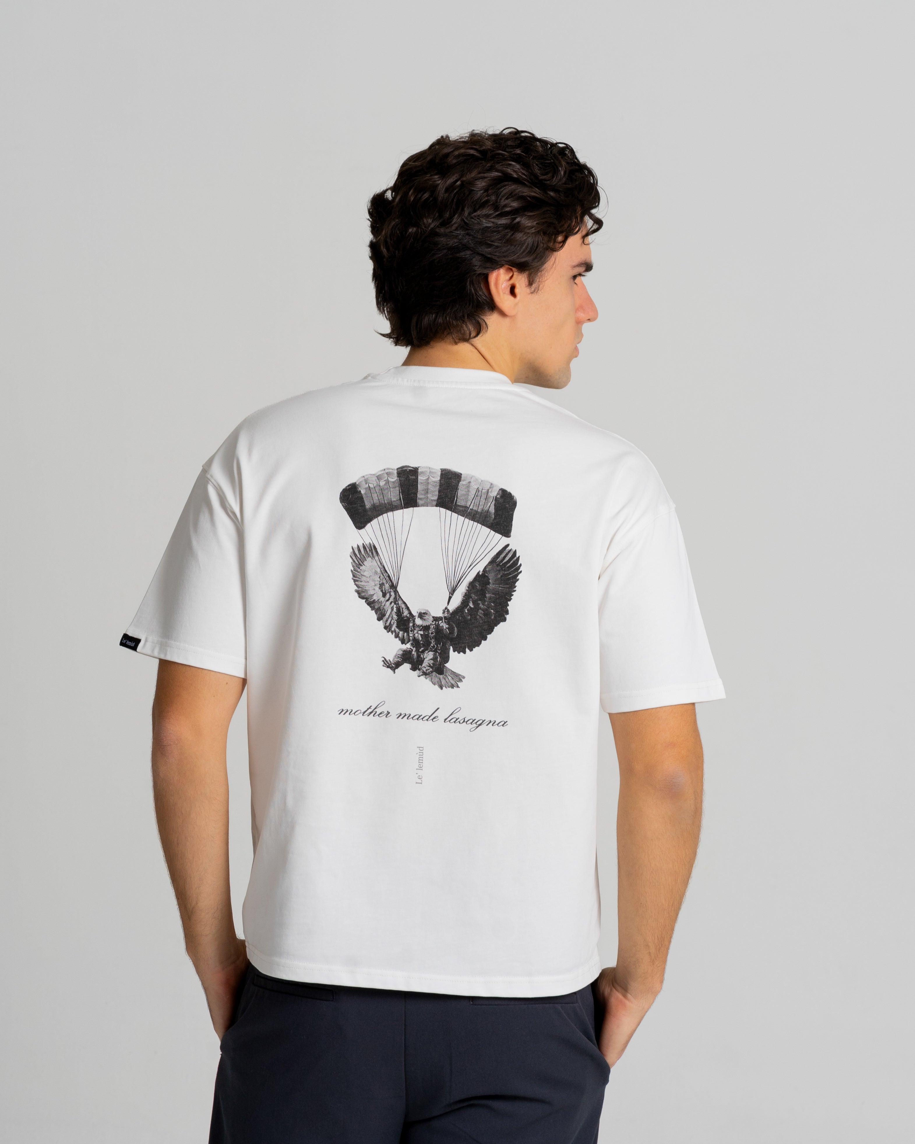 White oversized t-shirt with black eagle graphic on the back by Le Lemud, displayed on a white background